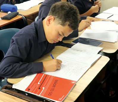 A student writing in a notebook during a Te Reo Māori class